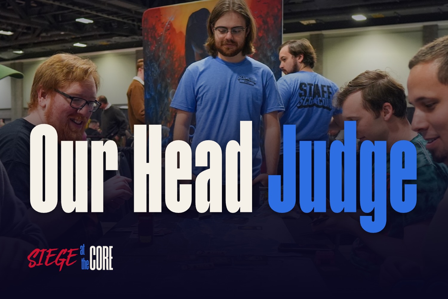 Zach, in blue, in the centre of the frame, overlooking players at the SCG-CON DC Grand Contest, with the words "Our Head Judge" and the Siege at the Core logo.